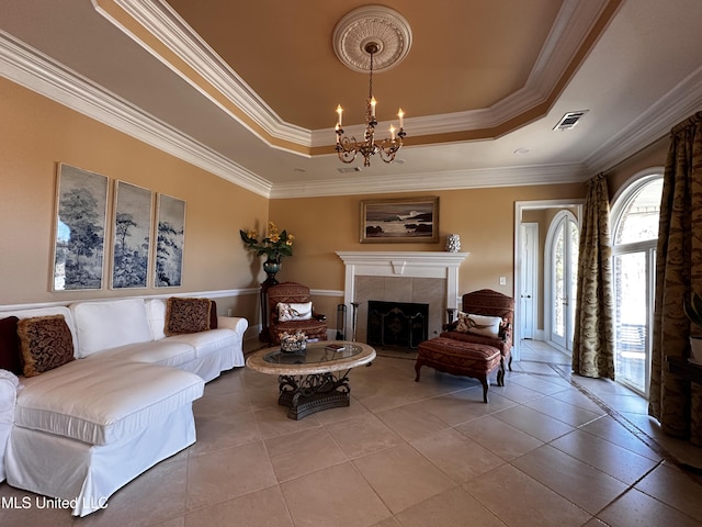 living room featuring tile patterned floors, crown molding, a chandelier, a raised ceiling, and a tile fireplace