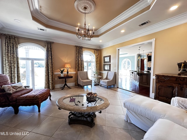 living area featuring a notable chandelier, a wealth of natural light, ornamental molding, and a raised ceiling