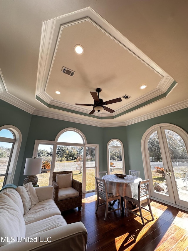 living room featuring dark hardwood / wood-style flooring, ornamental molding, ceiling fan, a raised ceiling, and french doors