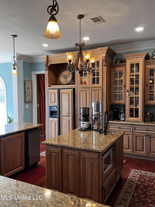 kitchen with sink, hanging light fixtures, stainless steel microwave, dark hardwood / wood-style floors, and a kitchen island with sink