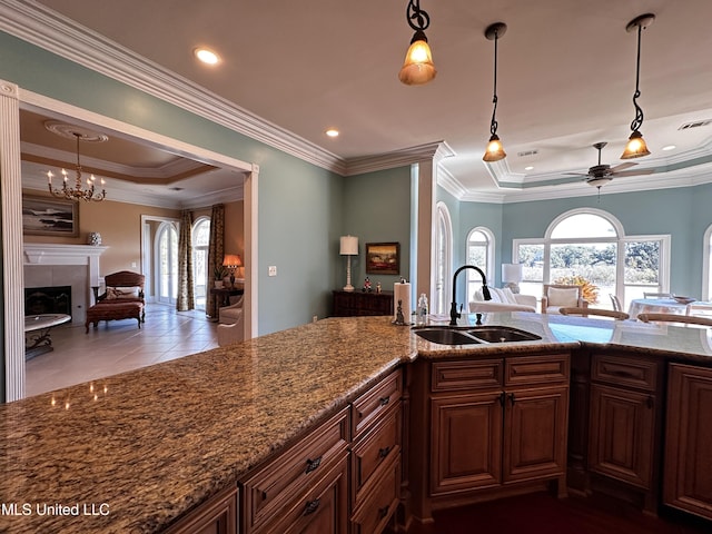 kitchen with a raised ceiling, plenty of natural light, sink, and light stone counters