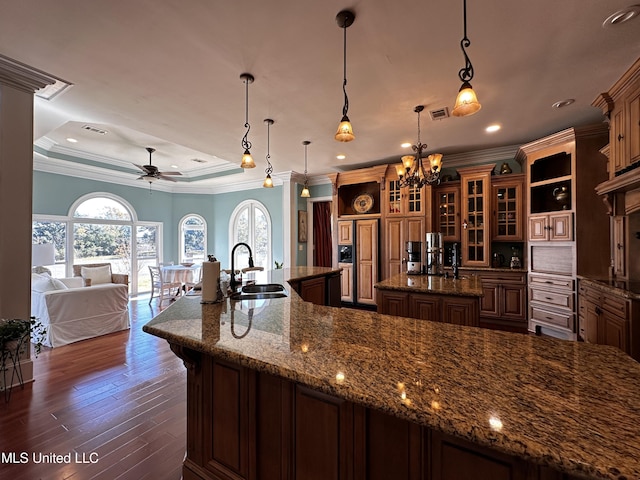 kitchen with a spacious island, dark wood-type flooring, sink, hanging light fixtures, and a tray ceiling