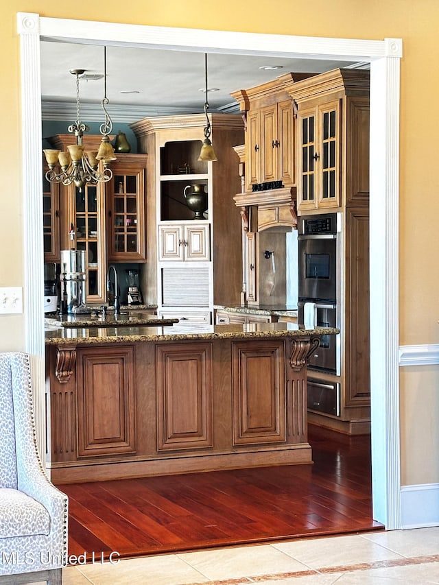 kitchen featuring pendant lighting, light hardwood / wood-style flooring, double oven, dark stone counters, and a chandelier