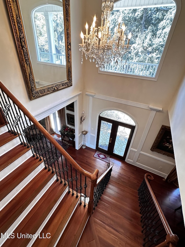 foyer featuring french doors, an inviting chandelier, hardwood / wood-style floors, and a high ceiling