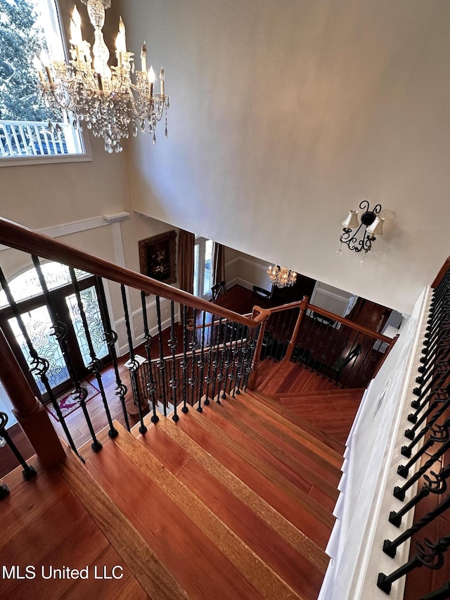 stairway featuring wood-type flooring and a notable chandelier