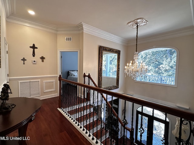 corridor with dark wood-type flooring, crown molding, and a notable chandelier