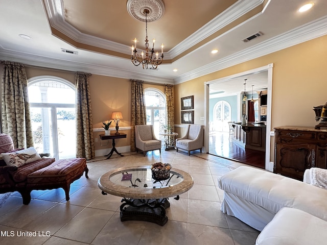 sitting room with a chandelier, ornamental molding, plenty of natural light, and a raised ceiling