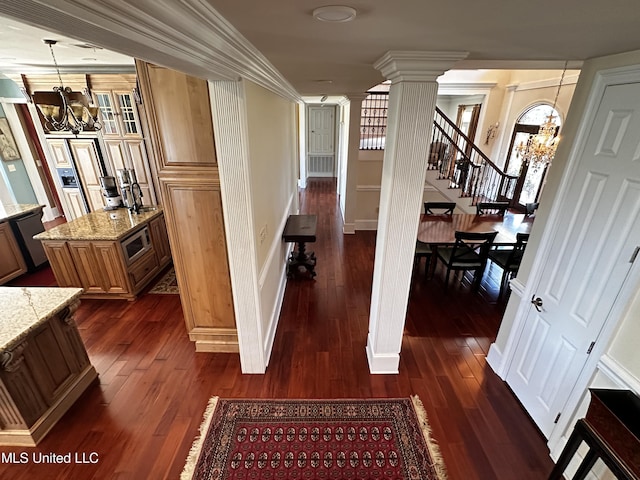 hall with ornate columns, dark wood-type flooring, and a chandelier