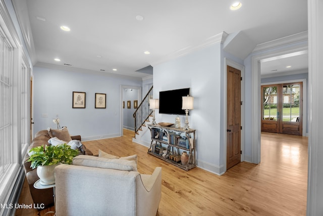 living room featuring crown molding, light hardwood / wood-style floors, and french doors