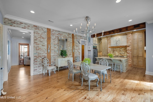 dining space featuring brick wall, ornamental molding, light hardwood / wood-style flooring, and a chandelier