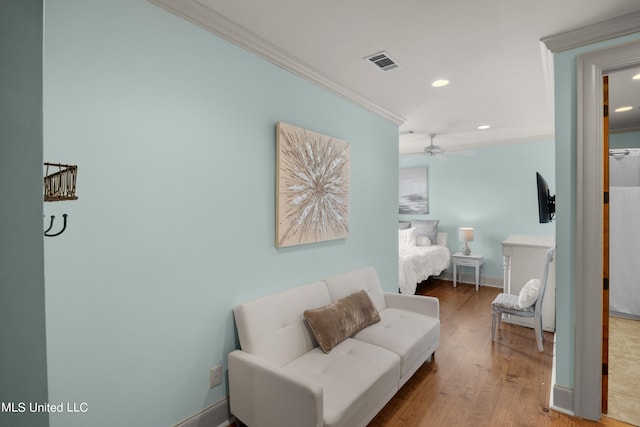 sitting room with crown molding, light wood-type flooring, and ceiling fan