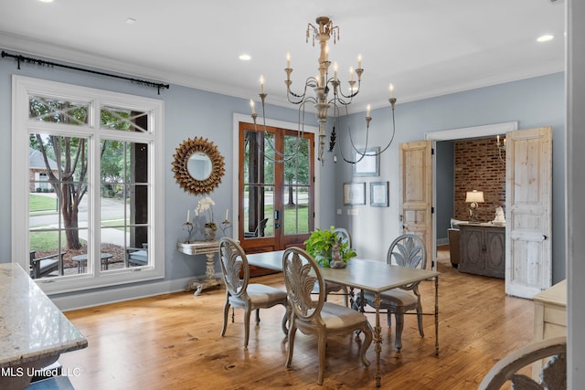 dining space with light hardwood / wood-style floors, a notable chandelier, plenty of natural light, and crown molding