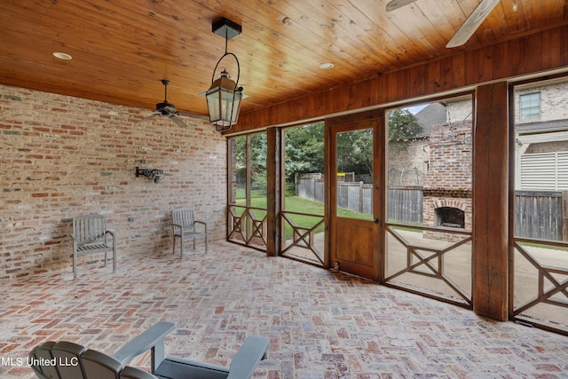 unfurnished sunroom with ceiling fan and wooden ceiling