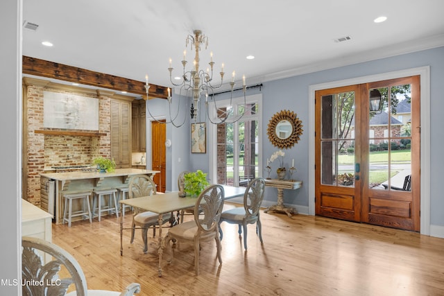 dining area featuring french doors, a notable chandelier, crown molding, and light wood-type flooring