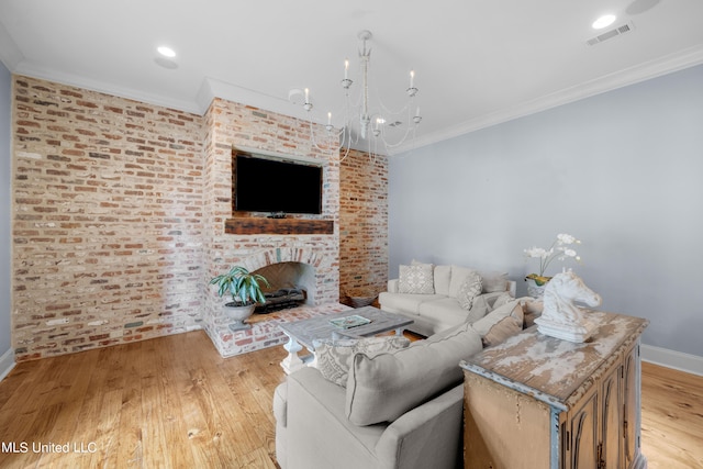 living room with an inviting chandelier, brick wall, crown molding, and light wood-type flooring