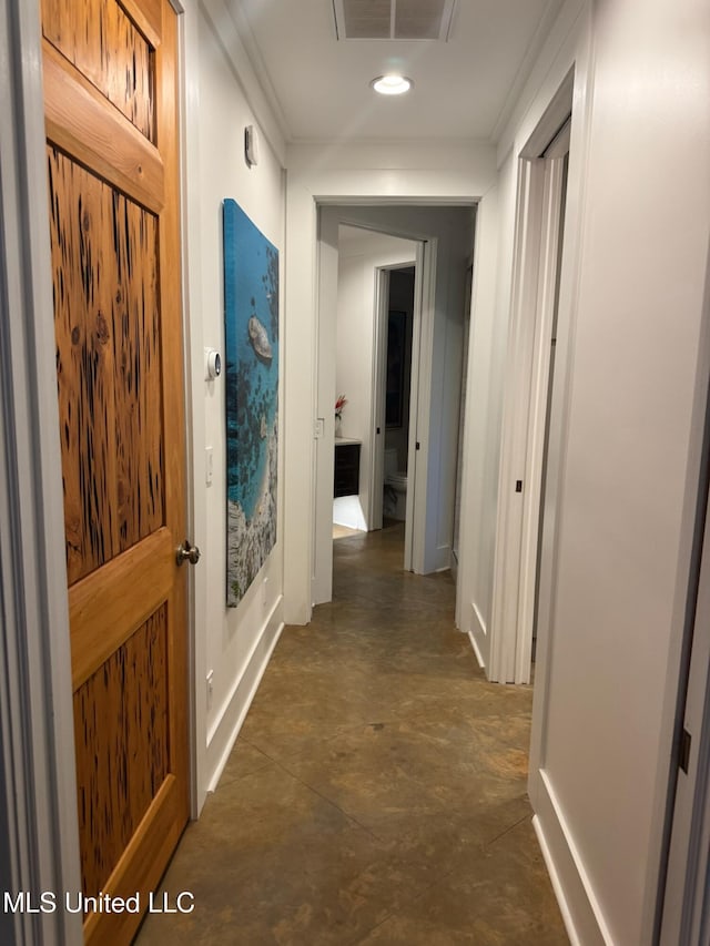 hallway featuring visible vents, concrete floors, baseboards, and ornamental molding