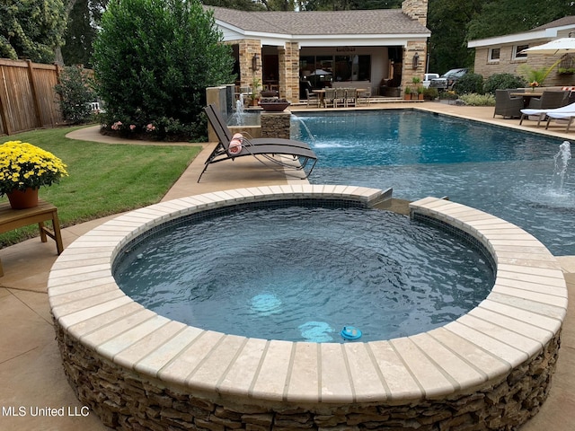 view of swimming pool with a patio area, a pool with connected hot tub, an outbuilding, and fence