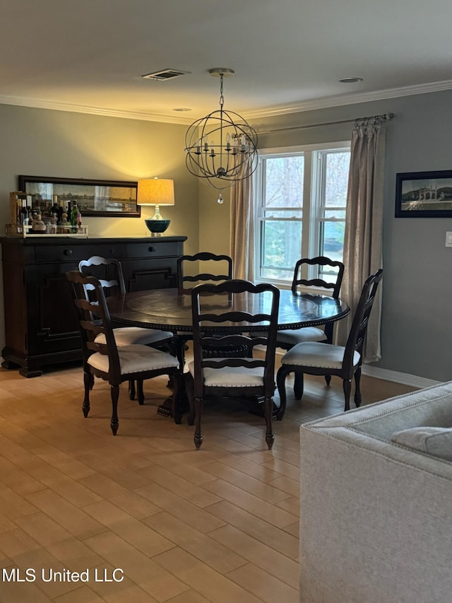 dining area featuring a notable chandelier, visible vents, light wood-style floors, and ornamental molding