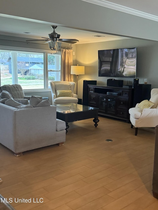 living room with a ceiling fan, crown molding, wood finished floors, and visible vents