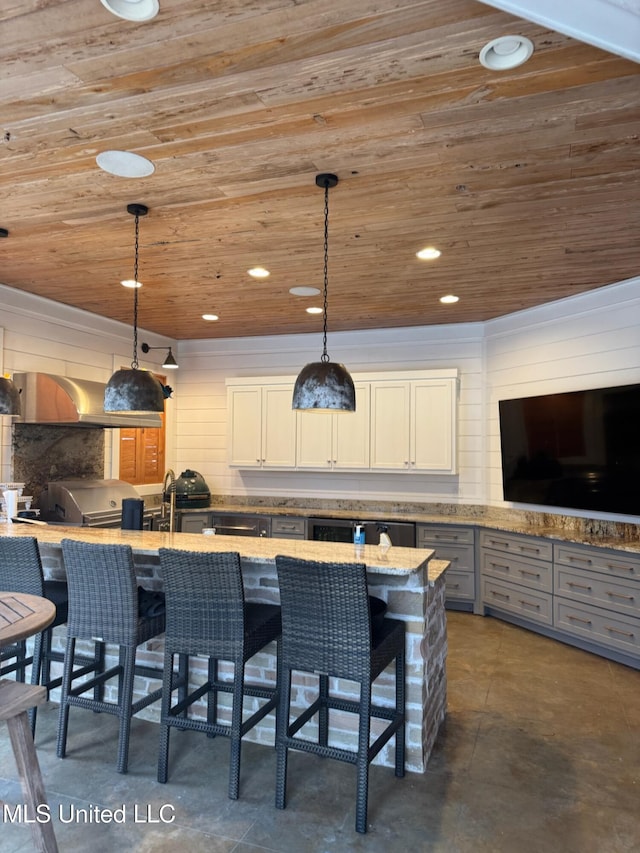 exterior space featuring a breakfast bar, light stone counters, decorative light fixtures, wooden ceiling, and decorative backsplash