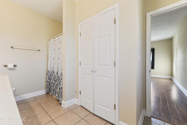 bathroom featuring curtained shower, hardwood / wood-style floors, and toilet