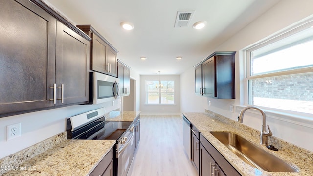 7881 Gardendale Dr, Olive Branch, MS 38654 - kitchen with stainless steel appliances, dark brown cabinets, light wood finished floors, light stone countertops, and recessed lighting