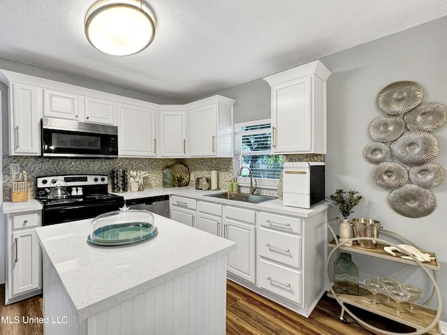 239 Palmetto Ln, Gulfport, MS 39507 - kitchen with appliances with stainless steel finishes, a sink, dark wood-style flooring, white cabinets, and a textured ceiling