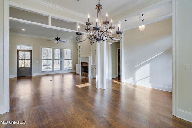 unfurnished living room featuring crown molding, baseboards, dark wood finished floors, ceiling fan with notable chandelier, and a fireplace