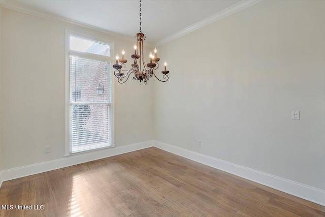 empty room with wood finished floors, a healthy amount of sunlight, a chandelier, and ornamental molding