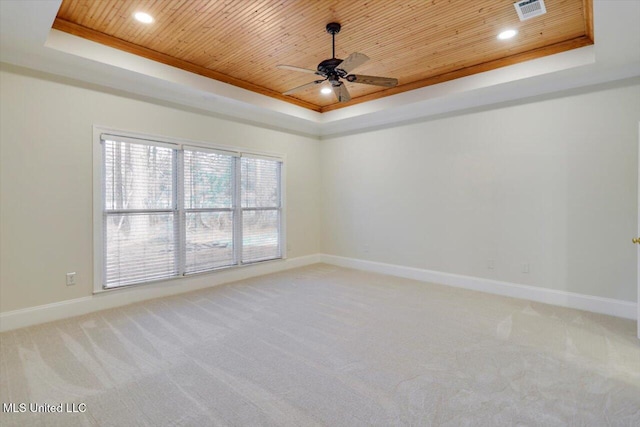 empty room featuring a tray ceiling and wooden ceiling