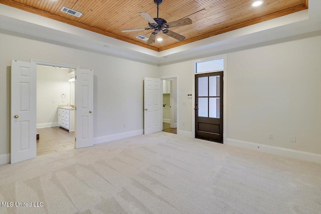 unfurnished bedroom featuring a raised ceiling, light colored carpet, visible vents, and wooden ceiling