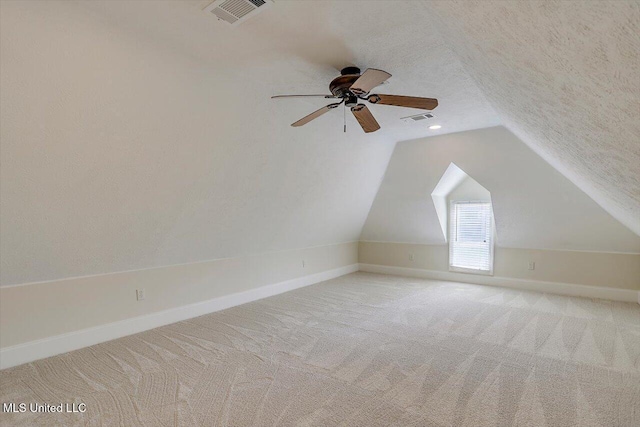 additional living space featuring vaulted ceiling, light colored carpet, visible vents, and a textured ceiling