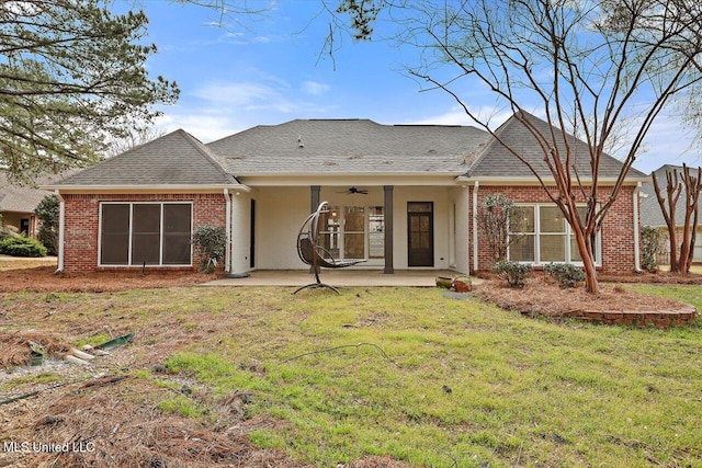 back of house featuring brick siding, a shingled roof, ceiling fan, a lawn, and a patio