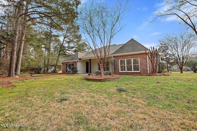 view of front of property featuring brick siding, a front lawn, and a shingled roof