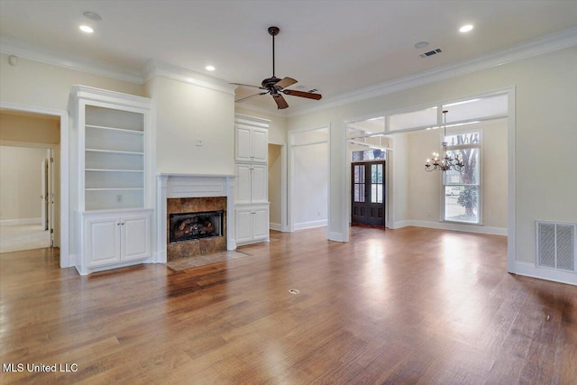 unfurnished living room featuring visible vents, ceiling fan with notable chandelier, crown molding, and a premium fireplace