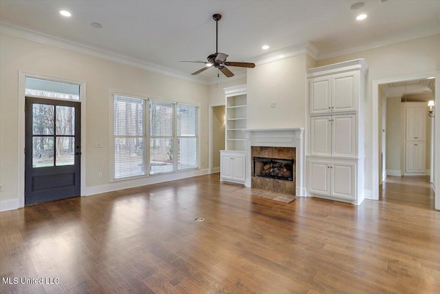 unfurnished living room with a fireplace, attic access, wood finished floors, and a ceiling fan