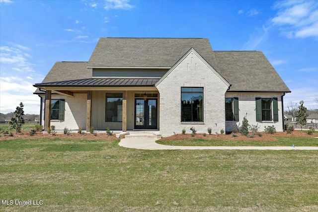 view of front of house featuring brick siding, a front yard, and a standing seam roof