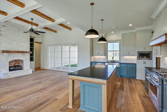 kitchen with light wood-type flooring, a fireplace, appliances with stainless steel finishes, beamed ceiling, and tasteful backsplash