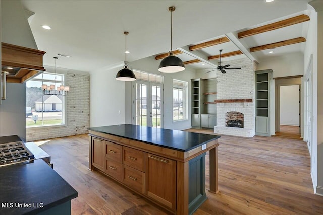 kitchen featuring wood finished floors, premium range hood, brick wall, a fireplace, and dark countertops