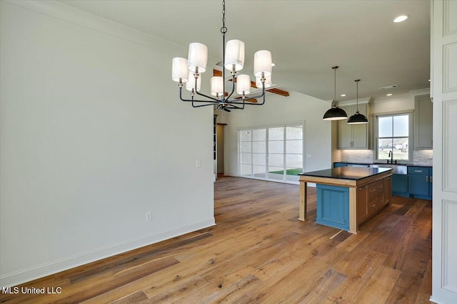 kitchen featuring wood finished floors, baseboards, decorative backsplash, dark countertops, and a center island