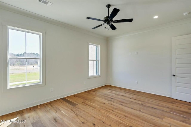 spare room featuring light wood-type flooring, visible vents, baseboards, and ornamental molding