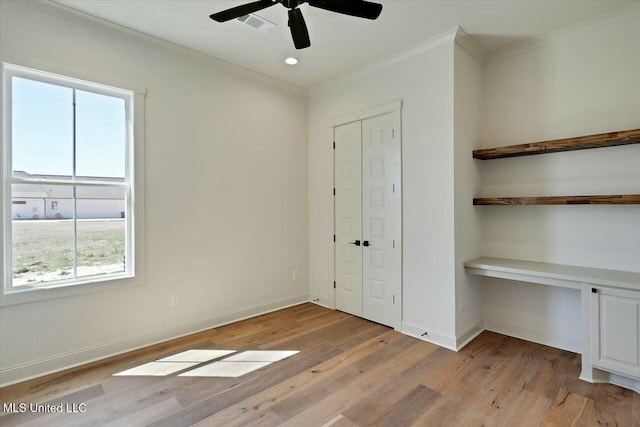 unfurnished bedroom with light wood-type flooring, baseboards, and built in desk