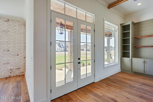 doorway to outside featuring light wood finished floors, french doors, recessed lighting, and brick wall