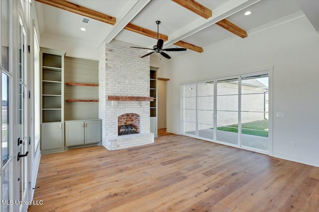 unfurnished living room featuring a brick fireplace, beamed ceiling, hardwood / wood-style flooring, coffered ceiling, and a ceiling fan