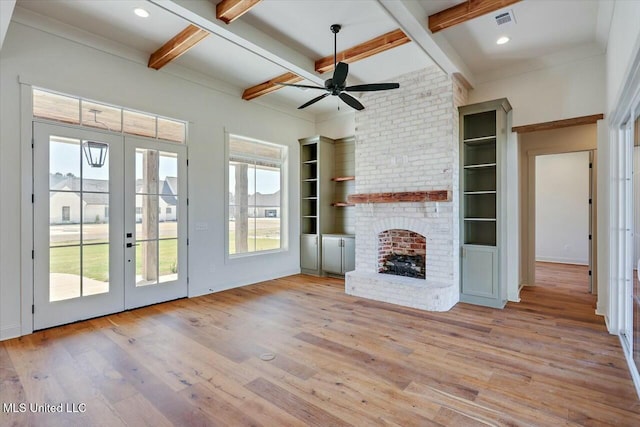 unfurnished living room featuring wood finished floors, a healthy amount of sunlight, coffered ceiling, a fireplace, and french doors