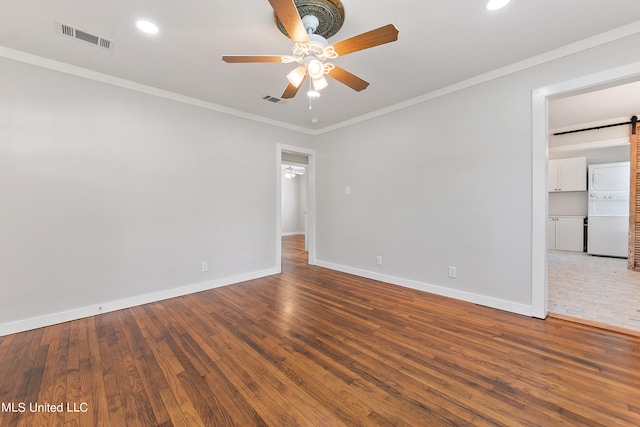 empty room featuring crown molding, a barn door, hardwood / wood-style flooring, and ceiling fan