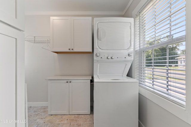 clothes washing area with cabinets and stacked washer and clothes dryer