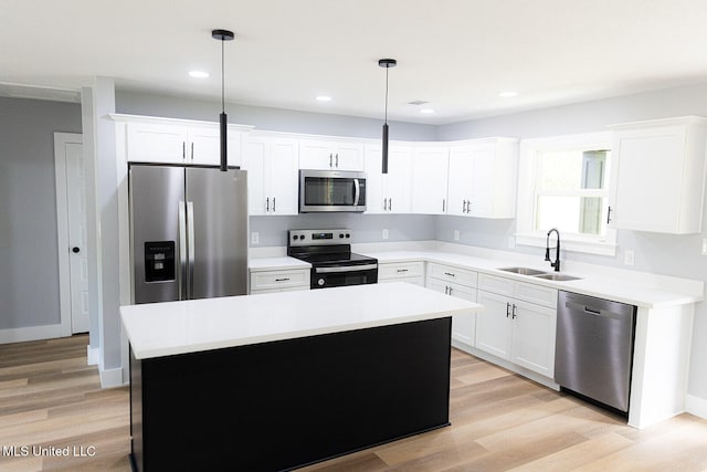 kitchen with appliances with stainless steel finishes, a sink, a kitchen island, white cabinets, and recessed lighting