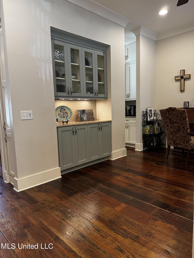 bar featuring gray cabinets, light stone countertops, dark hardwood / wood-style flooring, and decorative backsplash