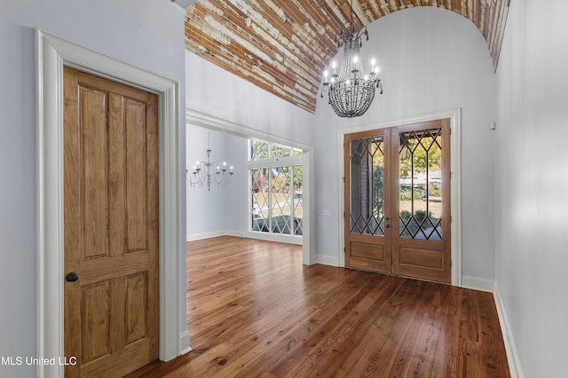 entryway with a chandelier, french doors, high vaulted ceiling, and wood-type flooring